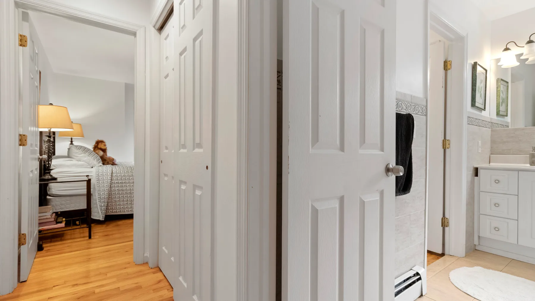 A bedroom is visible through an open doorway, with a bed and bedside lamp.