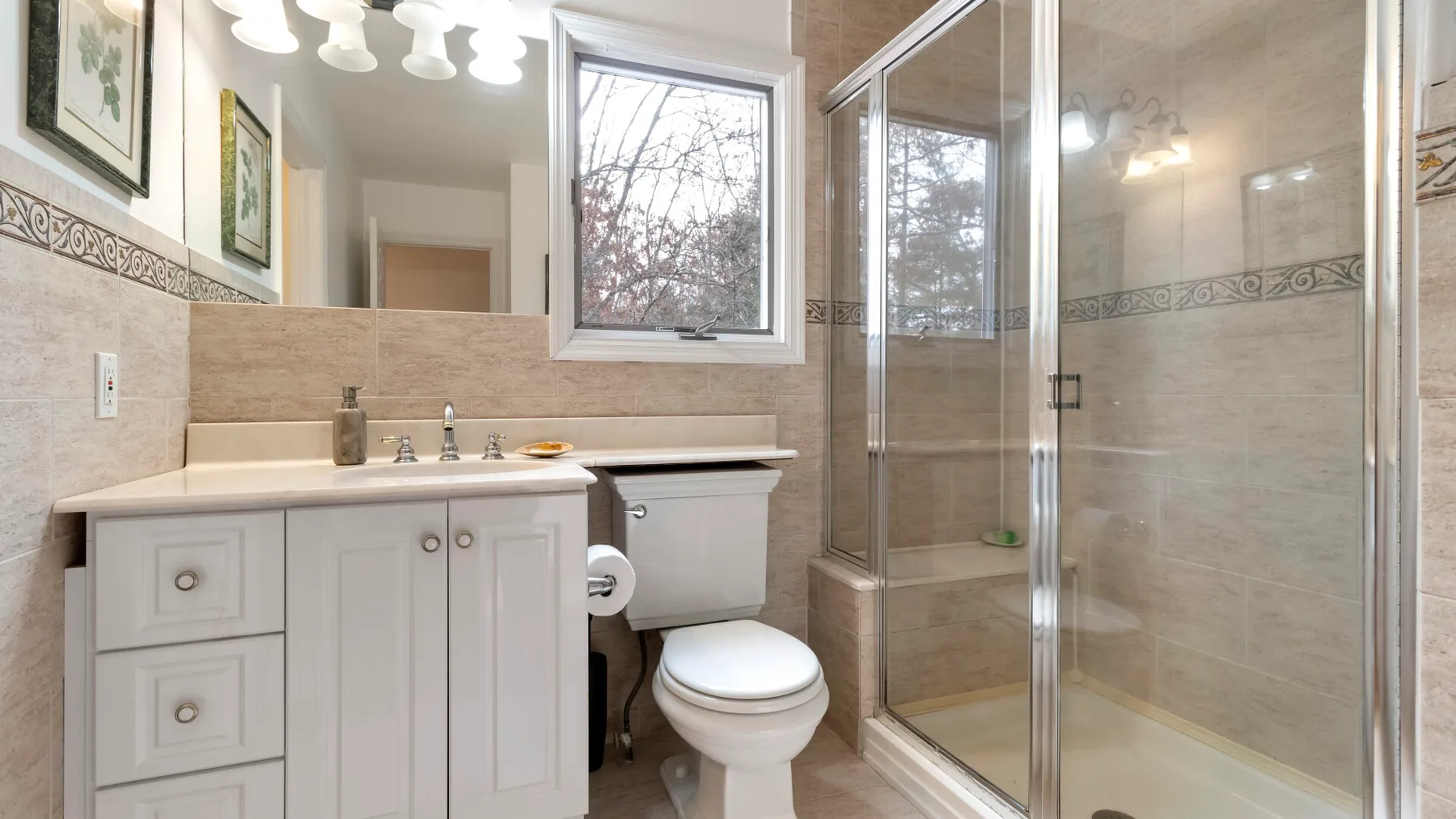 A bathroom with a vanity, toilet, and glass-enclosed shower.