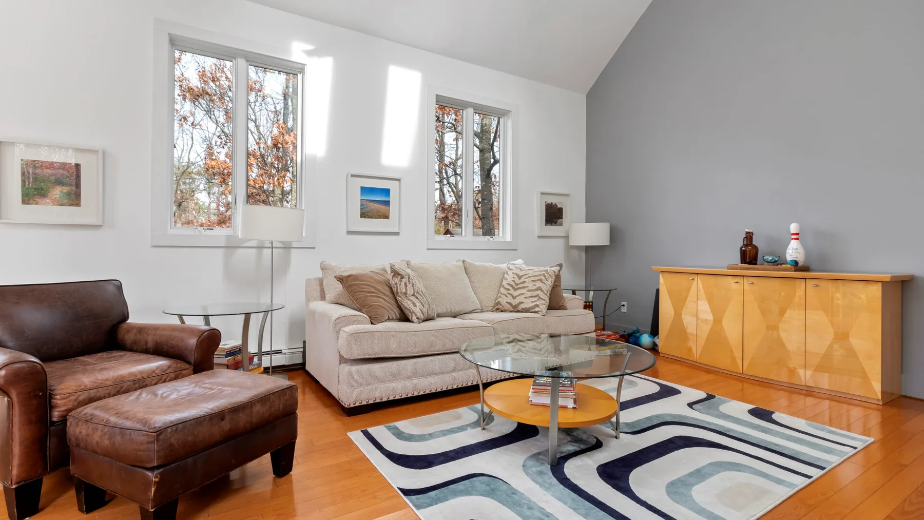 A bright living room with a seating area, glass tables, and large windows.
