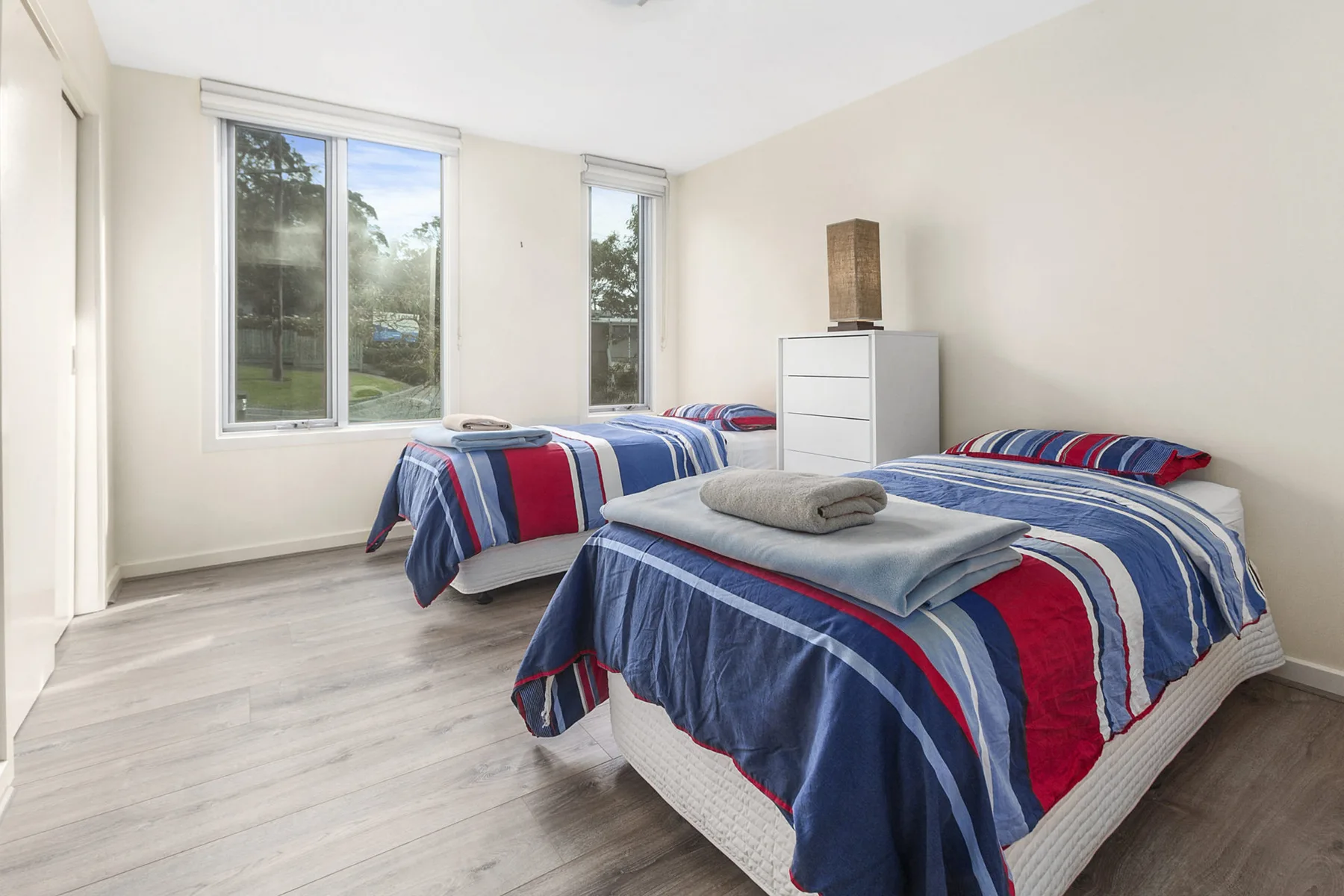 A bright bedroom with two beds dressed in striped bedding.