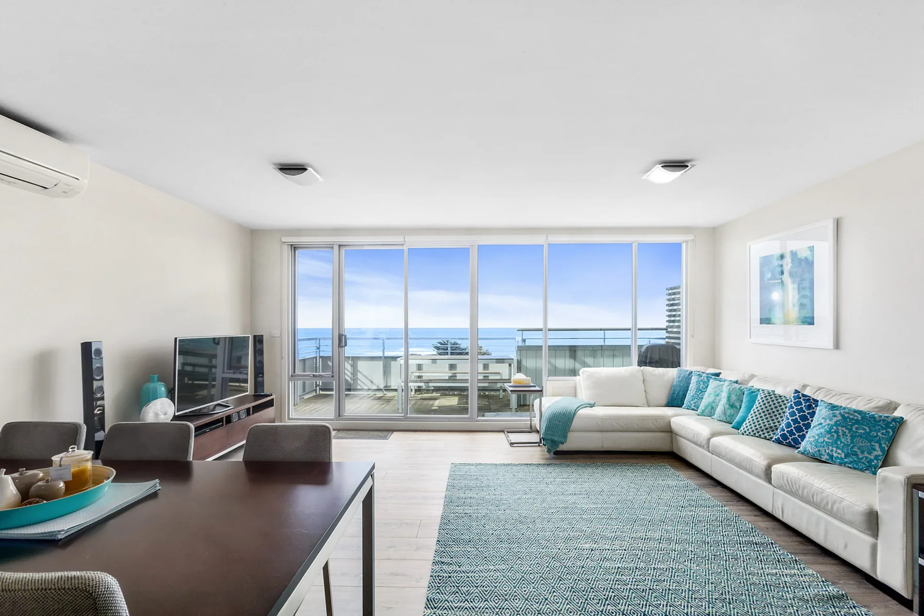 A bright living room with seating and large windows overlooking the water.