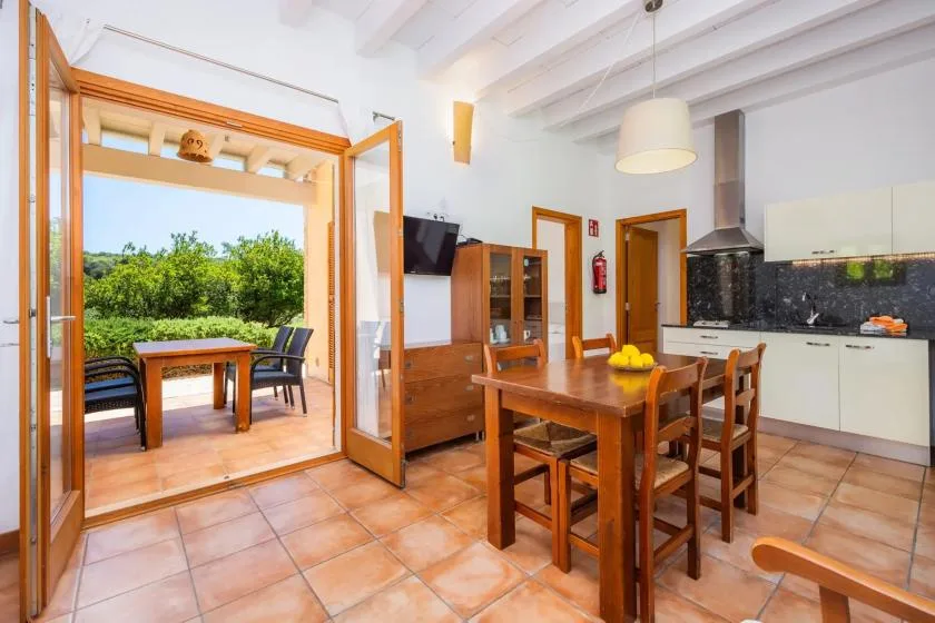 A dining area with a wooden table beside open doors to a garden.
