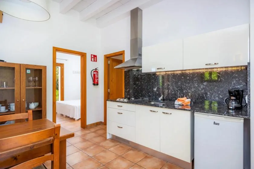 A bright kitchen with white cabinets, a dark backsplash, and wooden dining furniture.
