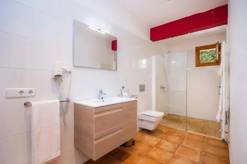 A bright bathroom with a vanity, mirror, toilet, and glass shower.