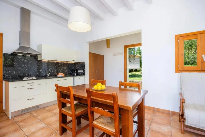 A bright kitchen and dining area with a wooden table and white cabinets.