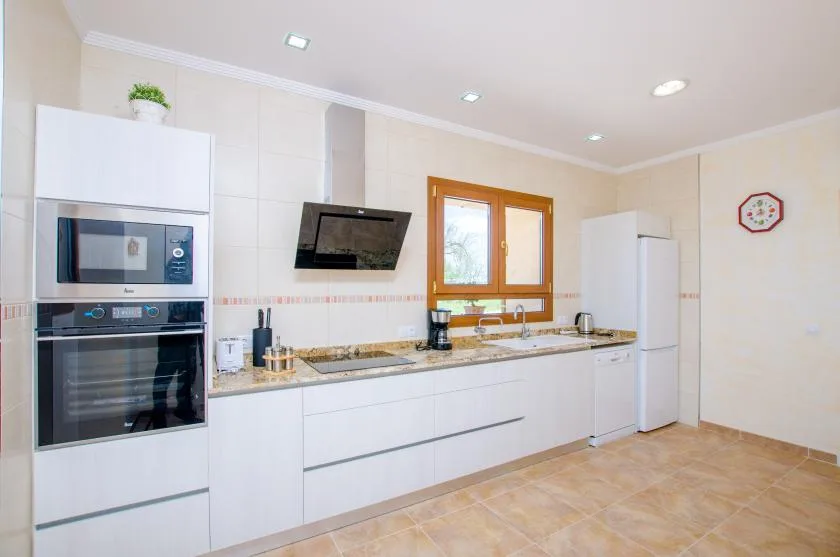 A bright kitchen with white cabinets, built-in appliances, and a window above the counter.