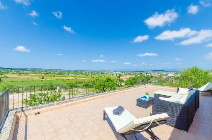 A tiled terrace has outdoor seating overlooking a green countryside landscape.