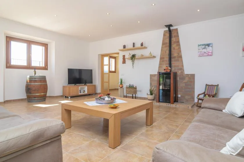 A bright living room with seating, a coffee table, and a brick fireplace.