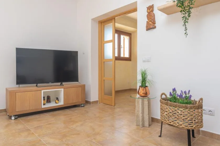 A living room with a television on a wooden console beside an open doorway.