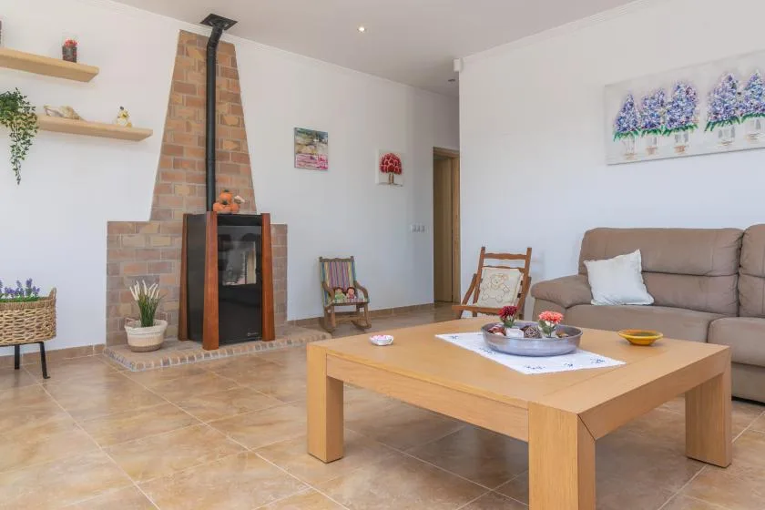 A living room with a brick fireplace, seating, and a wooden coffee table.