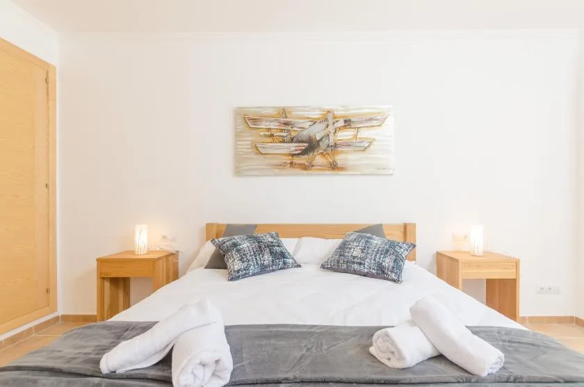 A bedroom with a double bed, bedside tables, and artwork above the headboard.
