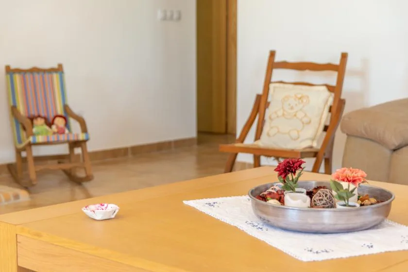 A living room with wooden seating and a low table holding a flower centerpiece.