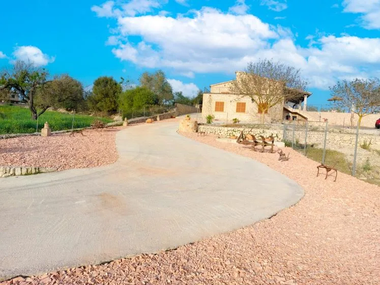 A paved driveway curves past a stone house and landscaped grounds.