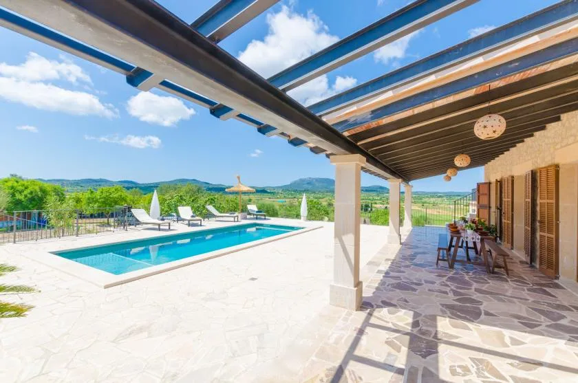 A swimming pool beside a covered patio with outdoor seating.