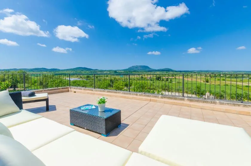 A rooftop terrace with outdoor seating and an open view of green hills.