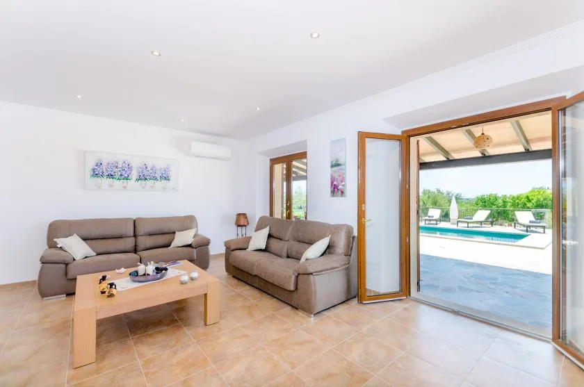 A living room with seating and a coffee table opens onto a pool terrace.