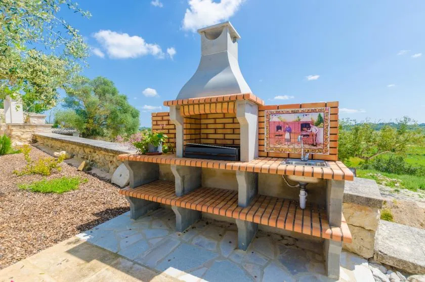An outdoor brick barbecue with a built-in grill and work surface.