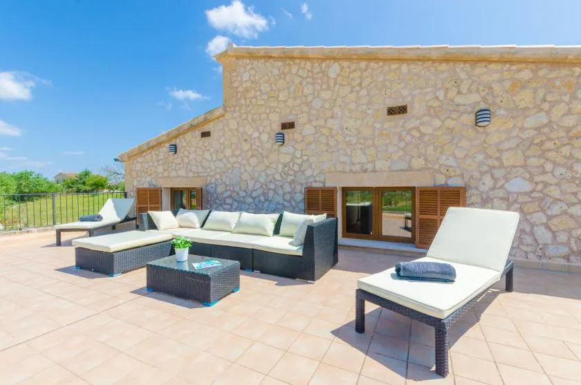 A sunny patio with outdoor seating beside a stone building.