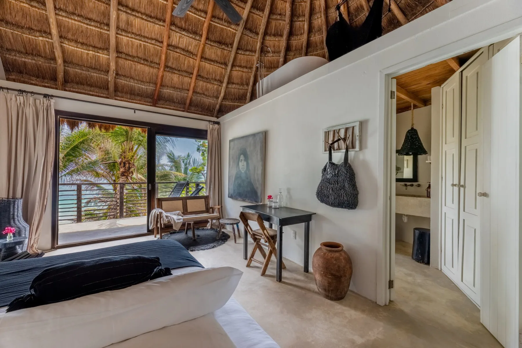 Guest room opening onto a terrace with palm trees outside