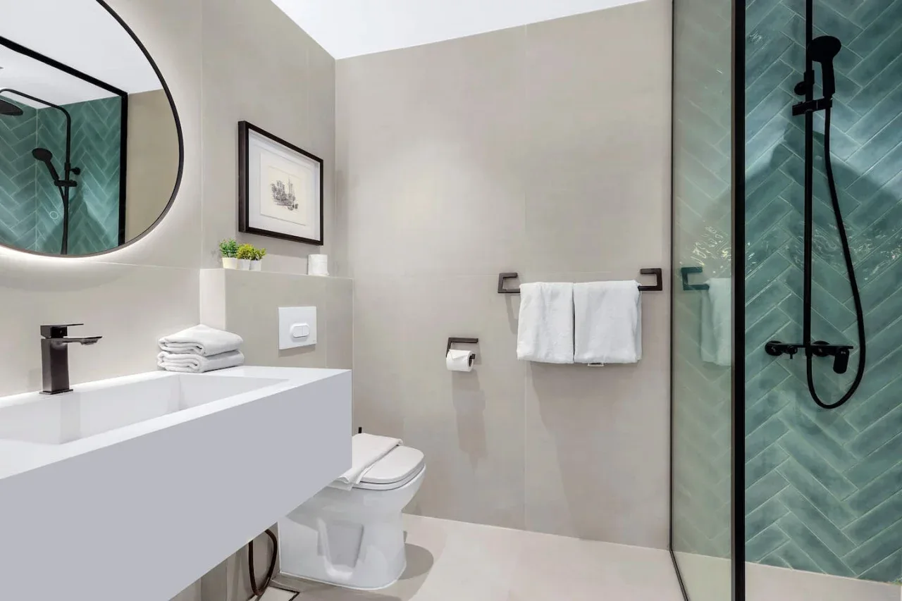 Un baño moderno con un lavabo amplio, inodoro y ducha de vidrio.
