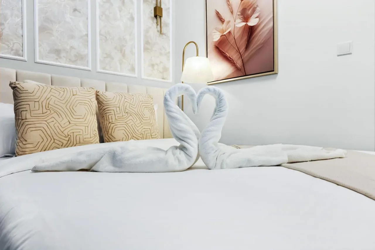 Una cama bien hecha muestra dos toallas dobladas en forma de cisne.