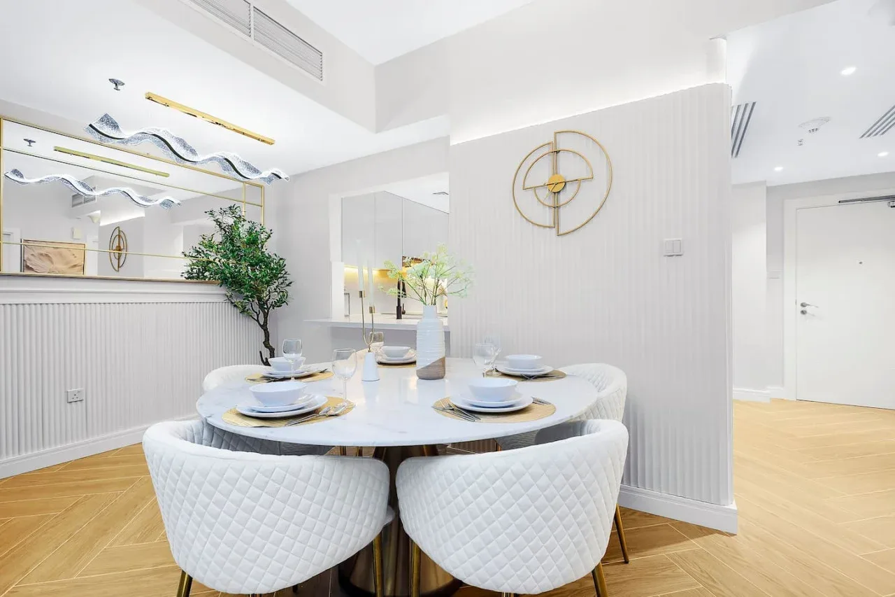 Un comedor luminoso con una mesa redonda puesta con platos y asientos.