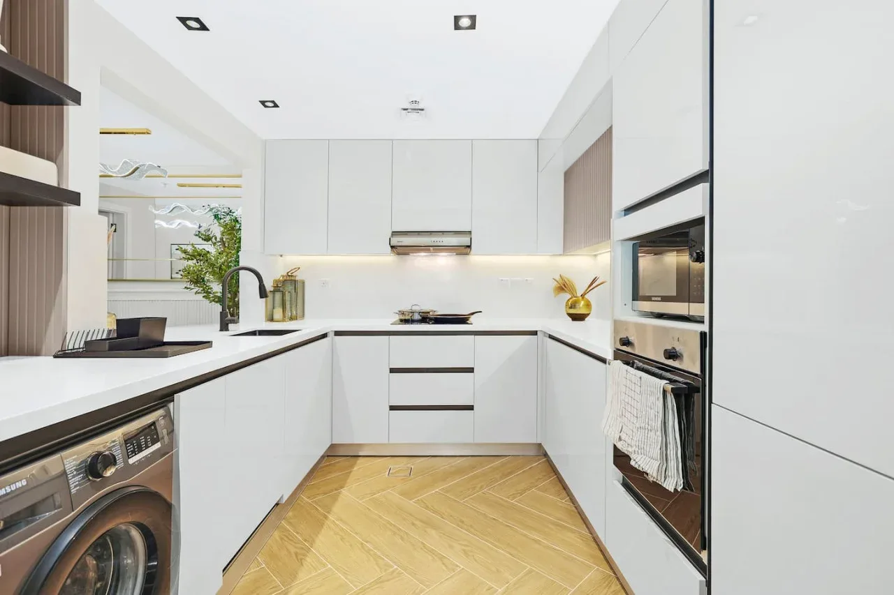 Una cocina moderna y luminosa con gabinetes blancos, una placa de cocina y electrodomésticos integrados.
