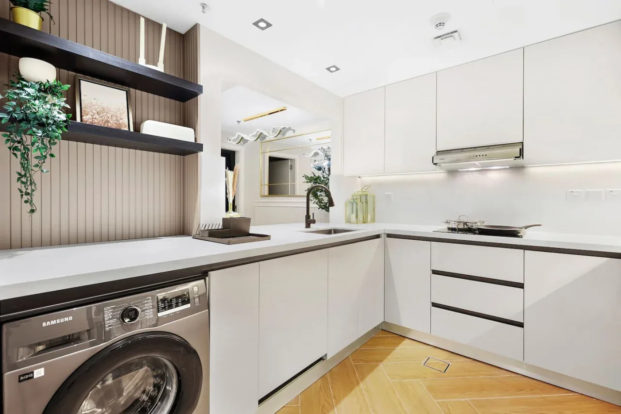 Una cocina moderna y luminosa con armarios blancos y una lavadora bajo la encimera.