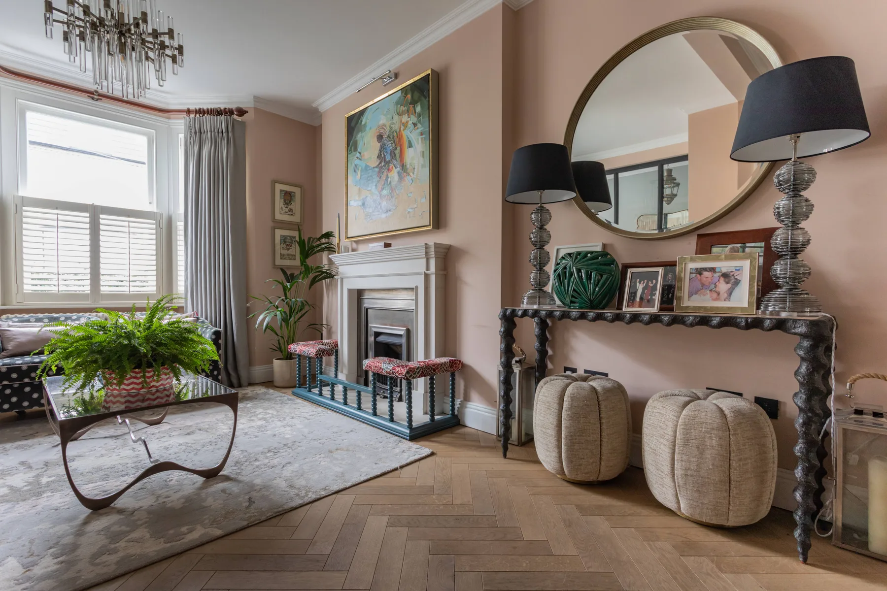 A living room with a fireplace, a large mirror, and seating by the window.