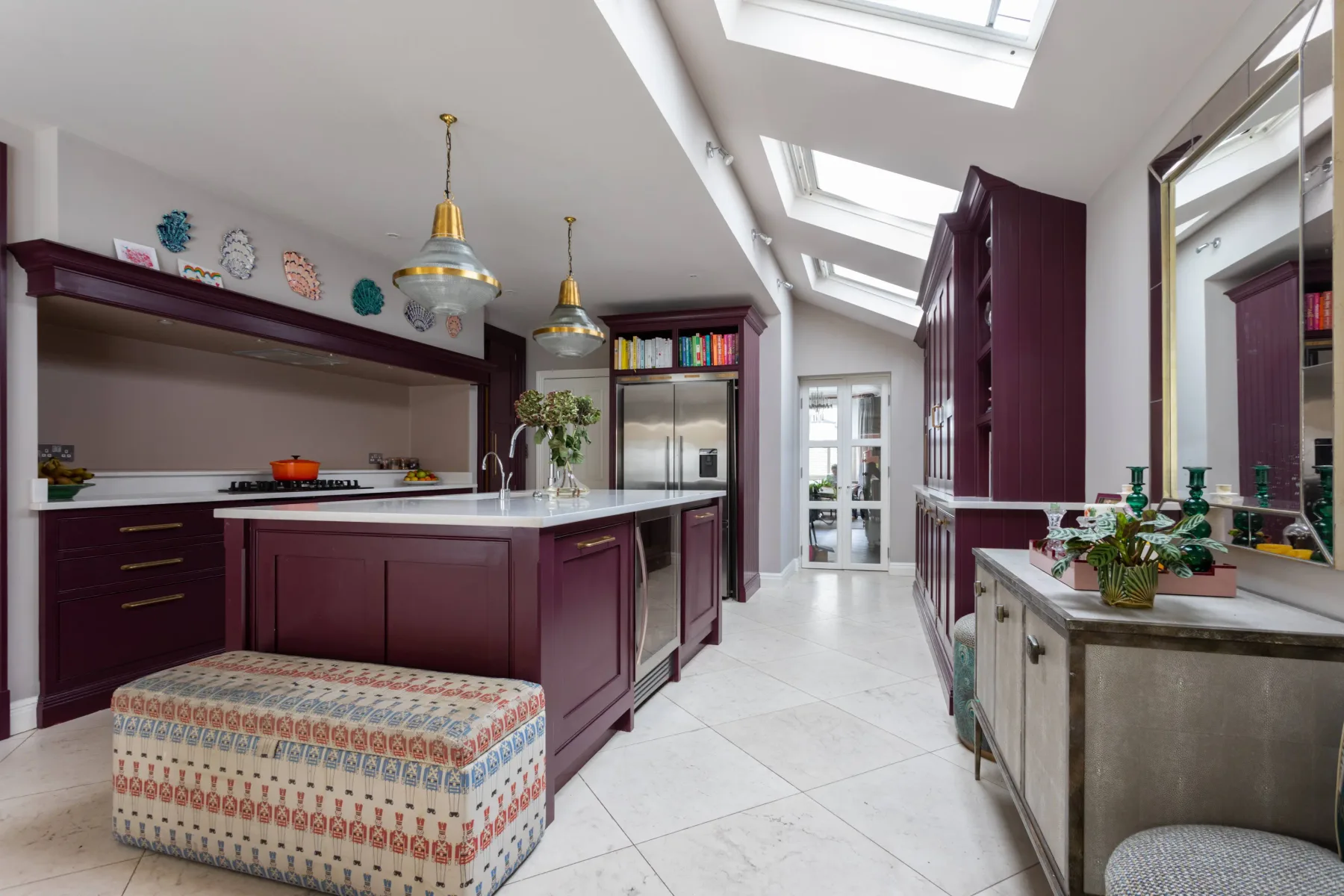 Una cocina luminosa con gabinetes color borgoña, tragaluces e isla central.