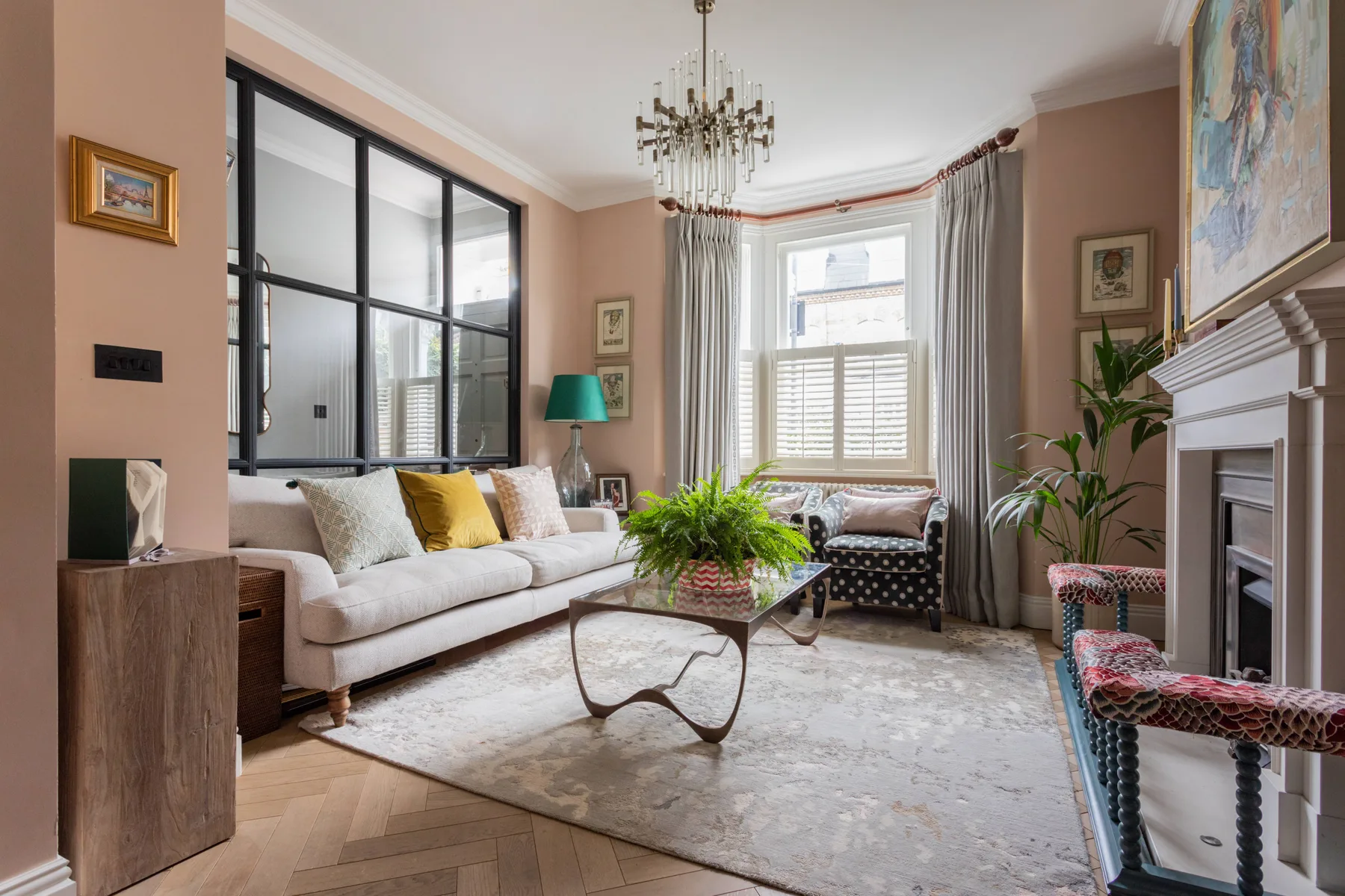 A living room with seating arranged around a coffee table beside large windows.