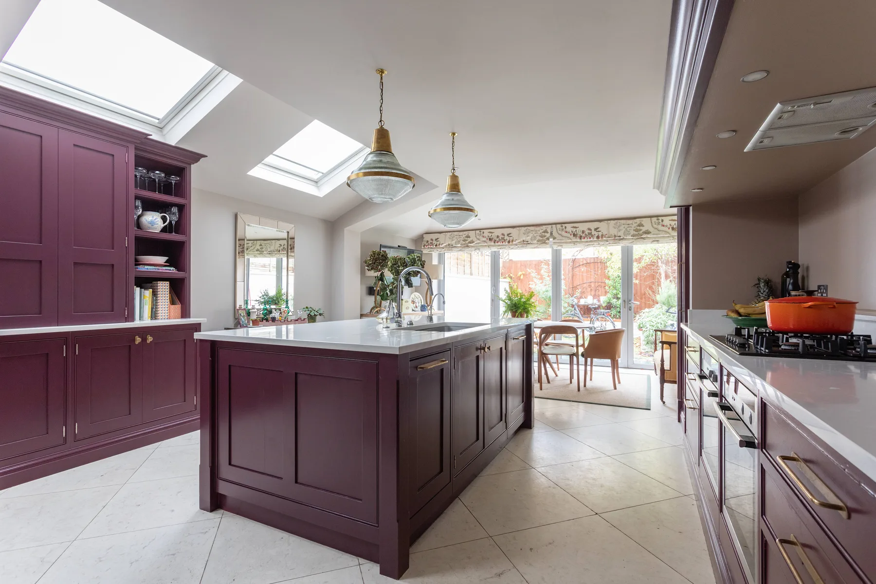 Una cocina luminosa con una isla central y grandes ventanas hacia el jardín.