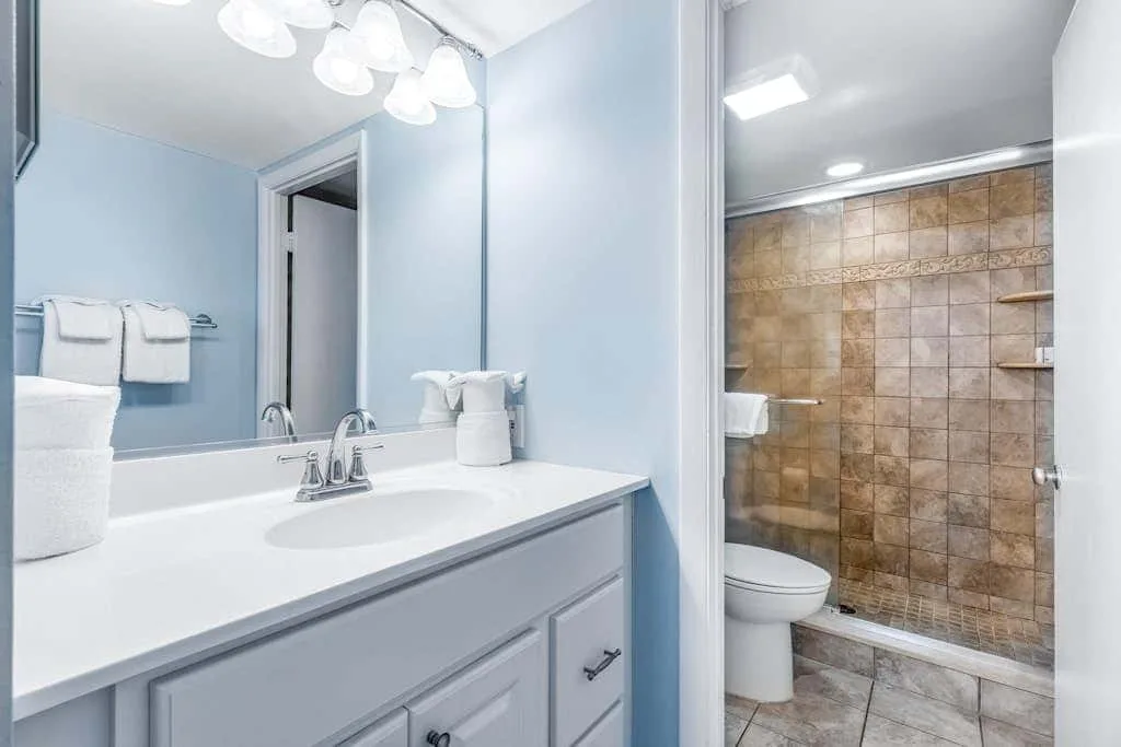 A bathroom vanity with a sink sits beside a tiled shower.