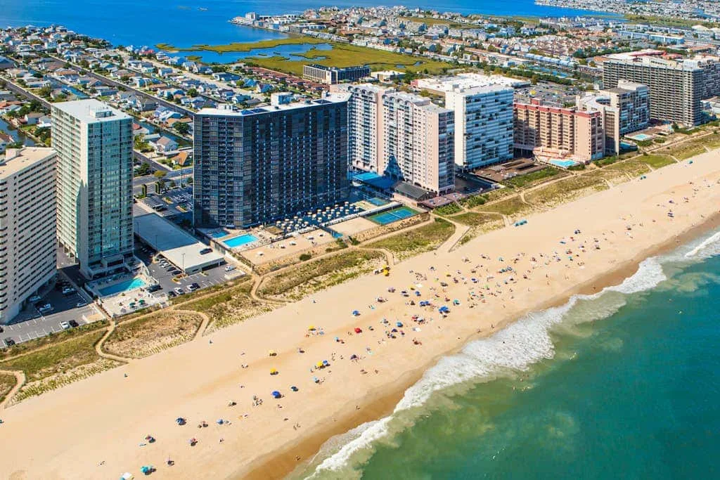 Aerial view of a sandy beach beside high-rise buildings and the ocean.