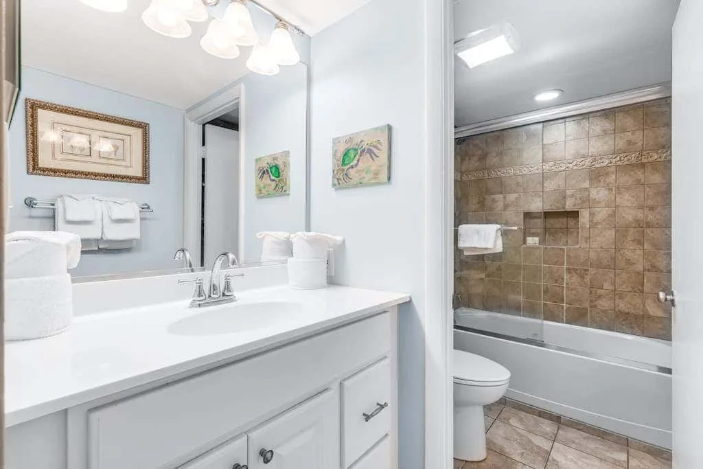 A bright bathroom with a vanity, sink, and bathtub.