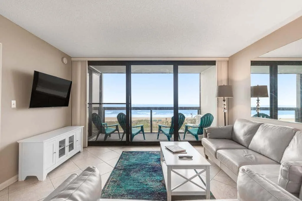 A living room with seating, a television, and sliding glass doors overlooking the water.