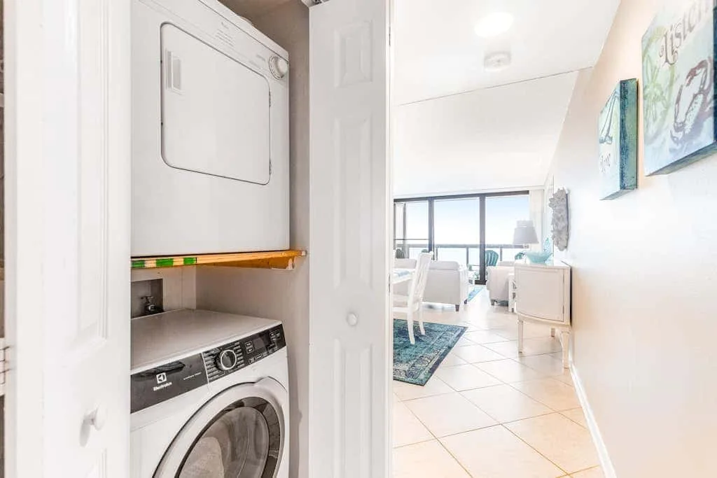 A laundry area opens onto a bright living space with tiled flooring.