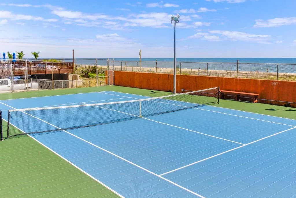 Outdoor tennis court with a net beside the sea.