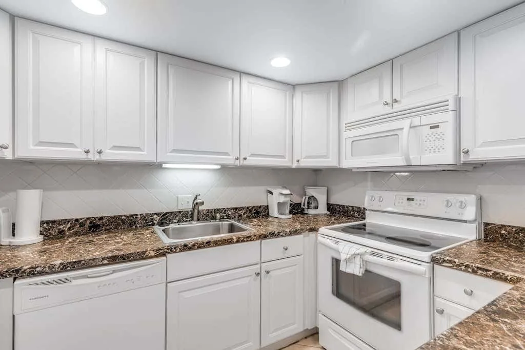 A bright kitchen with white cabinets, a countertop, and cooking appliances.
