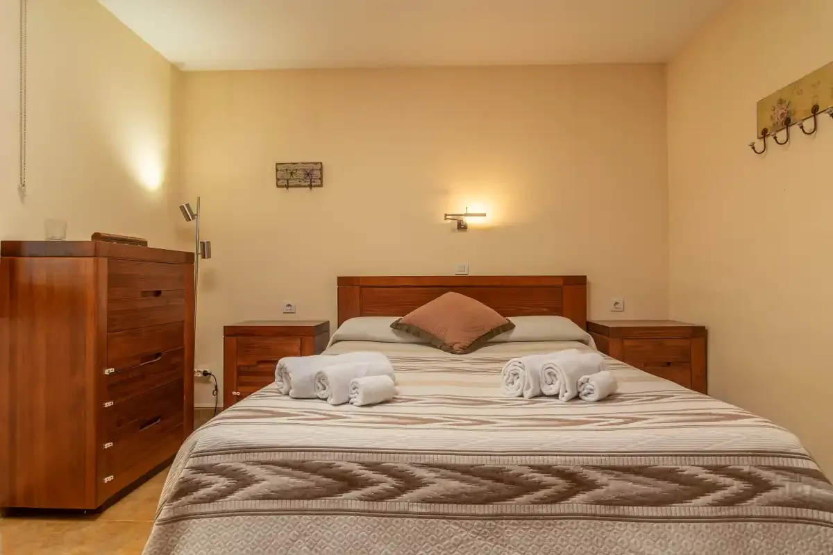 Un dormitorio con una cama bien hecha y toallas dobladas.