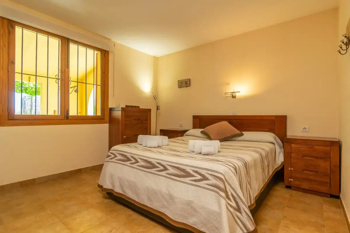Un dormitorio con una cama doble, mesillas de noche y una ventana.