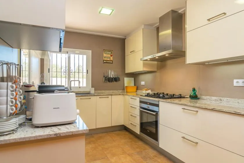 Una cocina luminosa con gabinetes claros, una encimera y una zona de cocción central.