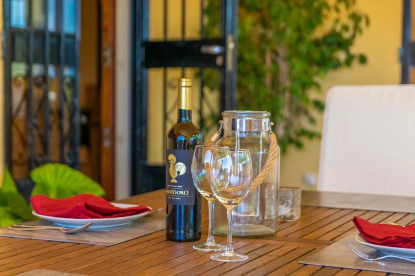 Una mesa de comedor está puesta con copas de vino y una botella.