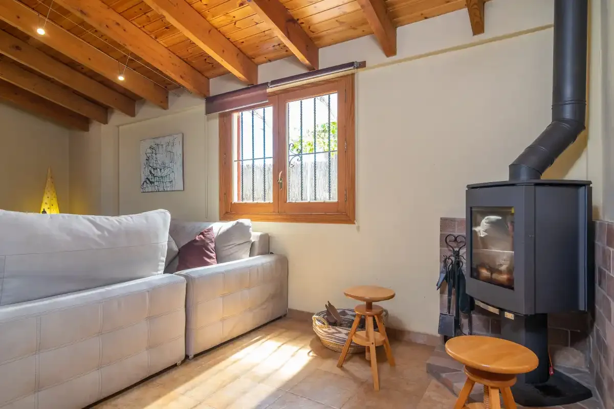 Una sala de estar con asientos, una estufa de leña y una ventana.