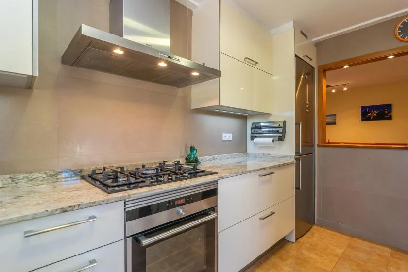 Una cocina moderna con gabinetes blancos, una placa de gas y un horno.