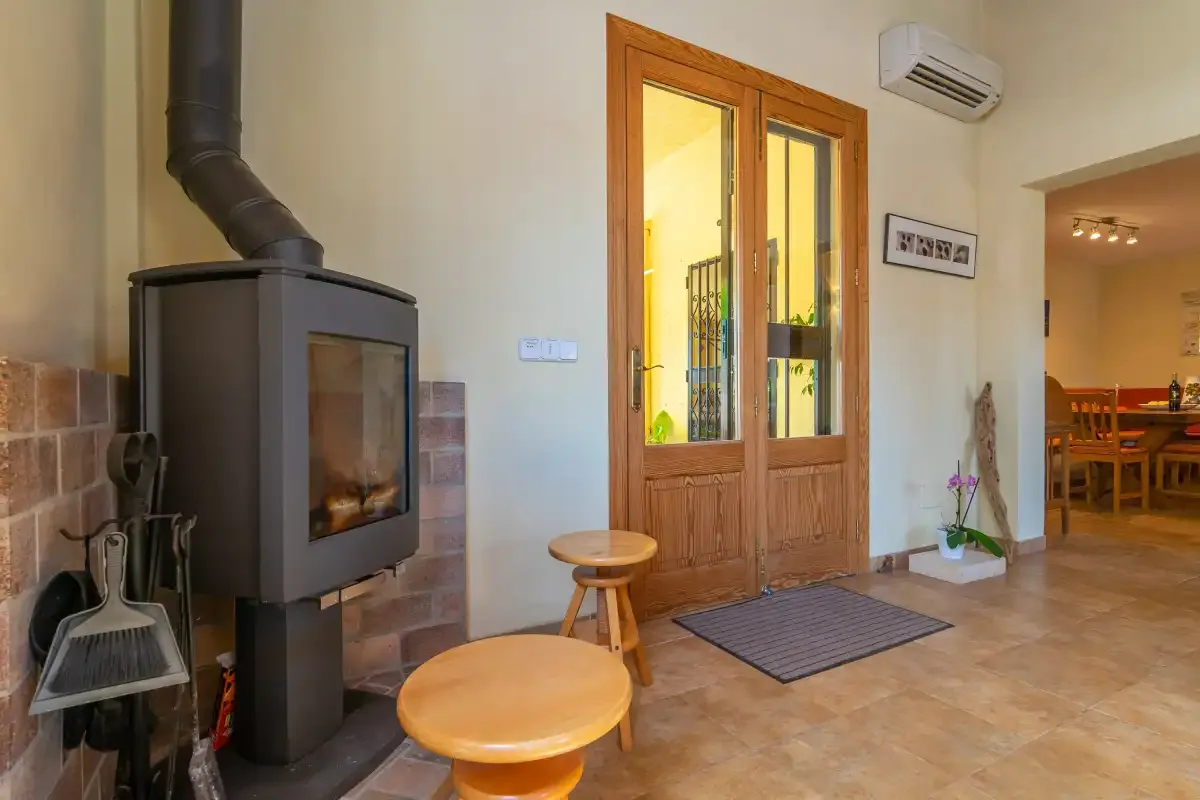 Una sala de estar con una estufa de leña junto a puertas de madera acristaladas.