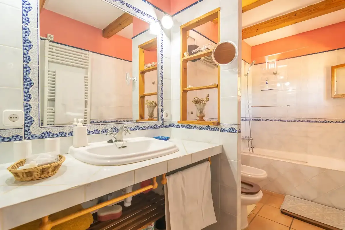 Un baño con azulejos, una encimera larga con lavabo y una bañera.