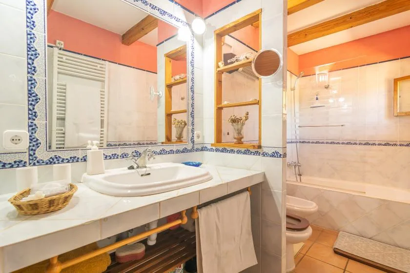 Un baño alicatado con lavabo, espejo y bañera.