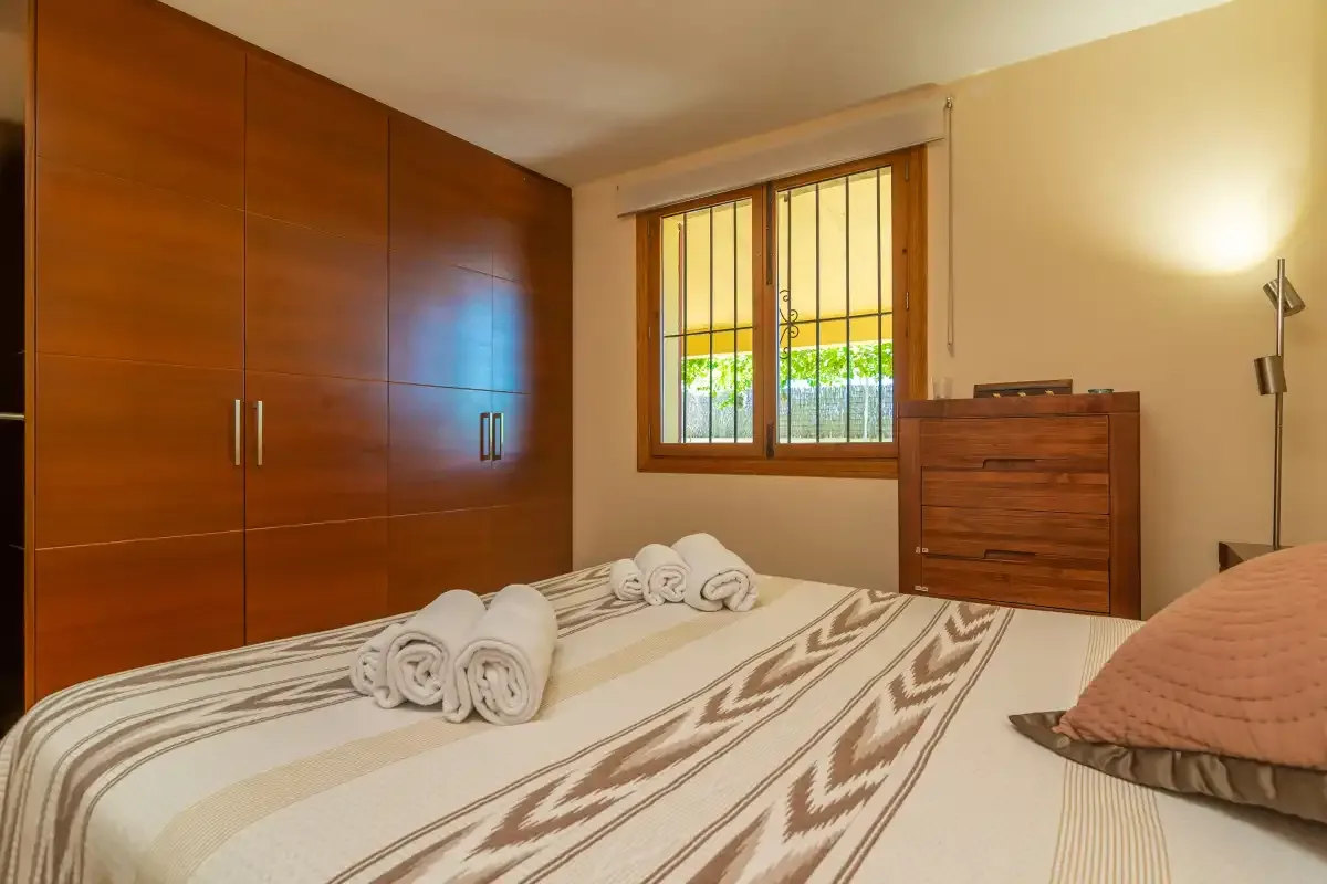 Un dormitorio con una cama a rayas, armarios de madera y una ventana.
