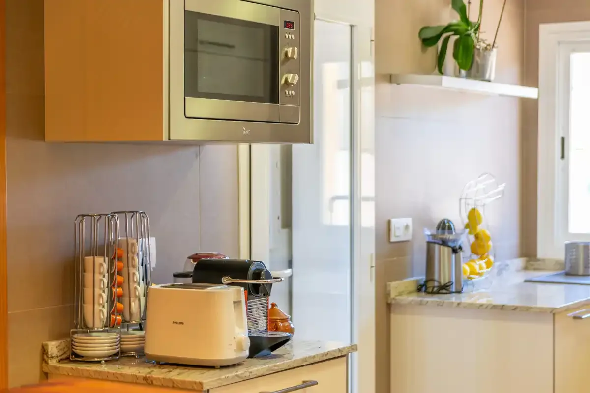 Una cocina luminosa con una tostadora sobre la encimera y un microondas empotrado.